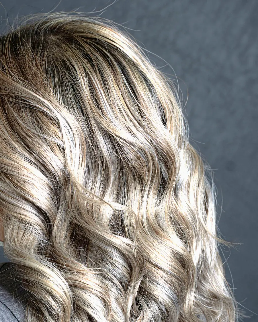 Schulterlanges Haar in weichen Wellen mit hellen Balayage-Strähnen, von hinten fotografiert.